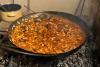 Una sartén honda con gazpacho manchego cocinándose sobre las brasas.