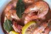 Gambas cocidas en cerveza con limón, laurel y pimienta en grano, todaví en el líquido de cocción.