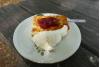 Un trozo de pastel de queso sueco, ostkaka, servido con mermelada de frutos rojos y nata montada.