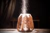 Un pandoro veronés ya hecho y enfriado a temperatura ambiente, espolvoreando azúcar glas antes de servir.