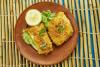Dos filetes de bacalao fresco rebozados en con y hechos en el horno, con una guarnición de lechuga y rodaja de limo2n.