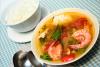 Un cuenco con gumbo de cangrejo, gambas y ocra con otra cuenco más peuquen1o con arroz blanco al lado.