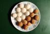 Un plato con bolitas de coco, narikol laru, hachas con azúcar blanco y azúcar moreno.