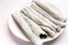 Un plato de loza blanca con rollitos de sésamo conocidos como til pita.