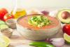 Cuenco de gazpacho mexicano decorado con aguacate y cilantro, rodeado de verduras frescas - imagen sintética.