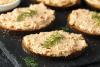 Rebanadas de pan tostado untadas con paté de salmón ahumado casero y decoradas con eneldo fresco.
