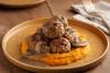 Albóndigas con salsa de champiñones y puré de batata servidas en plato rústico.