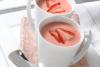 Dos tazas con gazpacho de fresas decorado con rodajas de fresa.