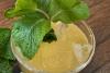 Limonada de maracuyá y menta con hielo y hojas de menta fresca en un vaso sobre una mesa de madera.