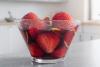Un recipiente con fresas al vino tinto con piel de naranja finamente cortada.