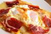 Detalle de unos huevos rotos con jamón serrano.