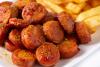 Salchicha alemana al curry, o currywurst, cortada en rodajas y acompañada con patatas fritas