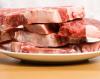 Cuatro filetes de carne en un plato blanco de loza.