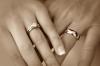Dos manos cogidas llevando anillos de matrimonio.