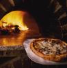 Horno con leña ardiendo y pizza recién hecha.