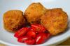 Croquetas de arroz y queso, arancini, recién hechas acompañadas de tomates miniatura.