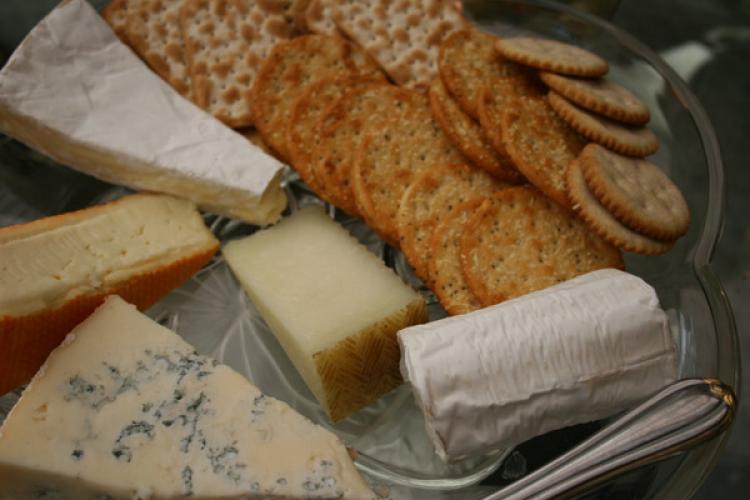 Una bandeja con varios tipos de queso y galletitas saladas.