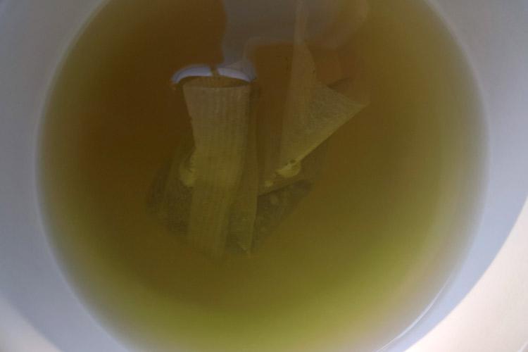 Taza con una bolsa de té verde en infusión.