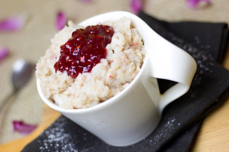 Una taza con budín de arroz al estilo y salsa de frambuesa.