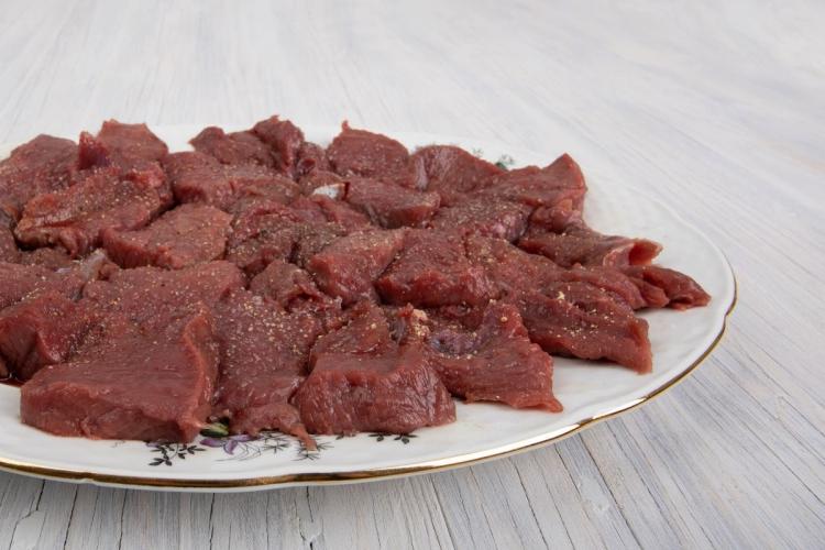 Un plato con carne cruda de ciervo, cortada y condimentada.