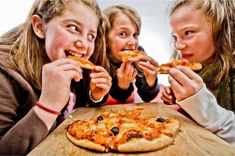 Adolescentes comiendo pizza casera.