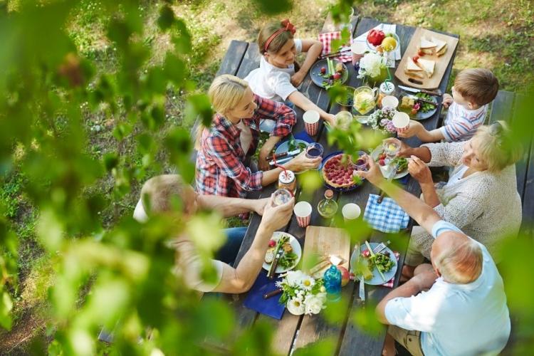 Familia disfrutando un picnic en una mesa de madera.