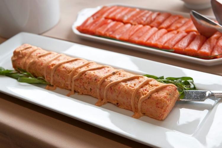 Mousse de salmón desmoldado y decorado con salsa rosa y hierbas.
