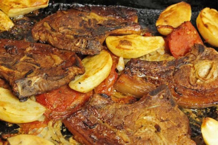 Chuletas de cerdo al horno con patatas y tomate.