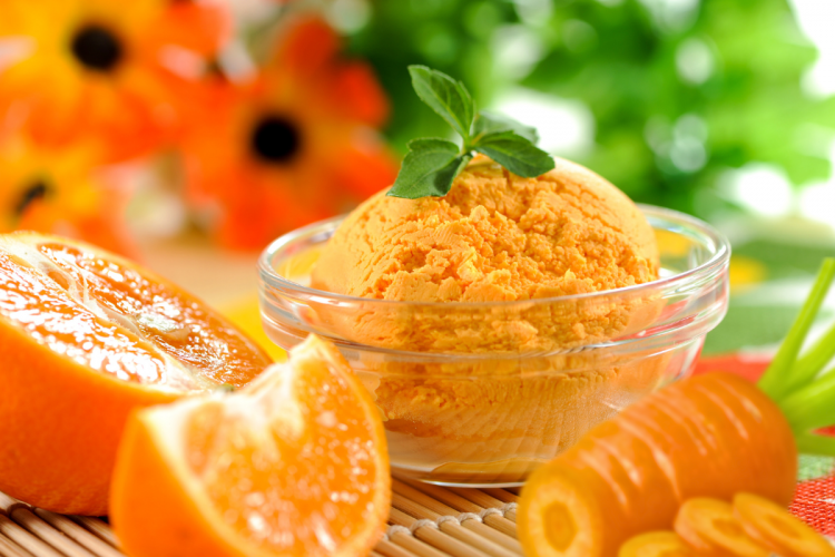 Un sorbete de zanahoria y naranja con algunos de los ingredientes alrededor.