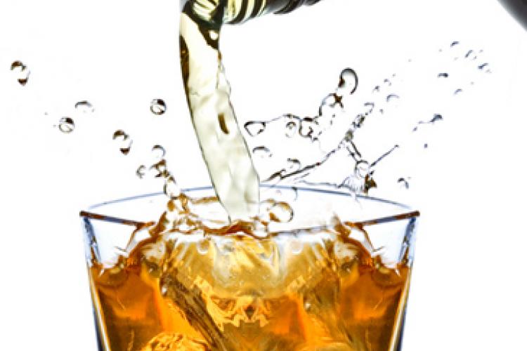 Whisky cayendo en un vaso con hielo.